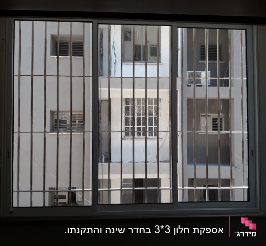 חלון זכוכית עם סורגים מול בניין סמוך
